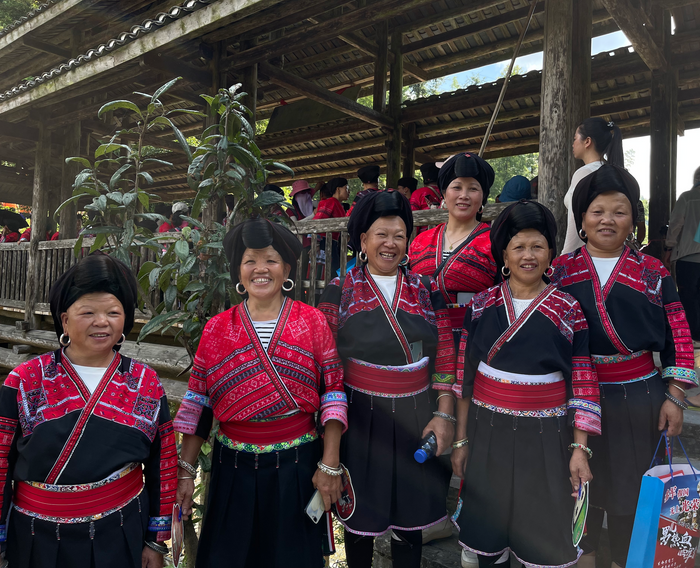 A group of smiling Red Yao women in traditional red and black clothing