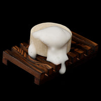 Lathered bar resting on a dark wooden soap tray