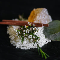 Rice, cinnamon sticks, white flowers and a crystal of resin on black